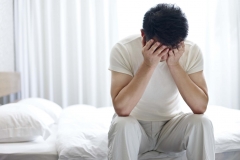 Photo of man sitting down with his head in his hands.