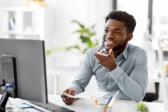 man at his computer speaking into phone