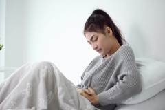 woman in bed with stomach pain