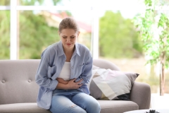Young woman suffering from endometriosis at home