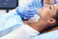 Adult woman having thyroind ultrasound test at female doctor's office