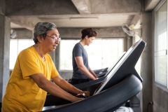 Healthy old man and American guy running on treadmill at fitness gym. family in sport center to exercise or workout for good health. Senior and young men exercise for Bodybuilding healthy lifestyle.