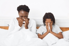 family using paper tissues while blowing nose and sneezing