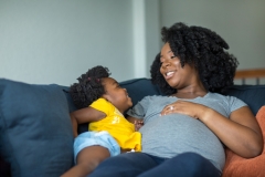 African American little girl talking with her pregnant mother.