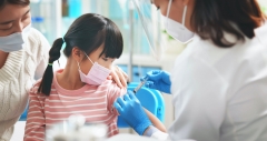 younger asian girl receives vaccine shot