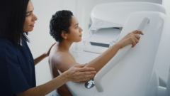 Friendly Female Doctor Explains the Mammogram Procedure to a Topless Latin Female Patient with Curly Hair Undergoing Mammography Scan.