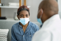 black women patient with face mask on meeting with her doctor