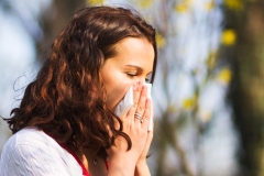 Woman blowing her nose in a spring day