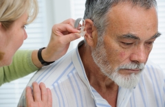 Photo of doctor inserting hearing aid in senior's ear