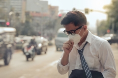 Business man wearing a mask and coughing on the street.