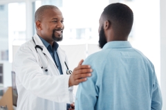 Doctor, black man and touch shoulder of patient for support, comfort and empathy in hospital