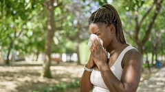 woman using tissue with pollen allergy at park