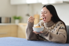 Happy asian woman eating cereals in winter in the kitchen at home