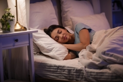 Beautiful young happy woman sleeping on bed in evening at home