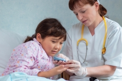 Asian girl at hospital getting her blood sugar measured by doctor or nurse during medical health check-up to prevent diabetes