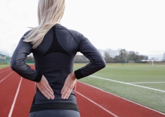 Athletic fitness woman rubbing the muscles of her lower back. Sports exercising injury.