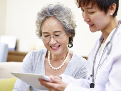 senior asian woman and family doctor having a discussing using tablet computer