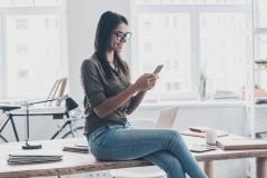 woman checks her phone at the office