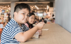 obese child eating at food court