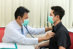 Senior Asian doctor examining male patient in the hospital.Doctor listening patient's heartbeat.
