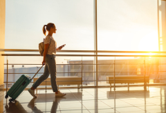 young woman goes at airport at window with a suitcase waiting for plan